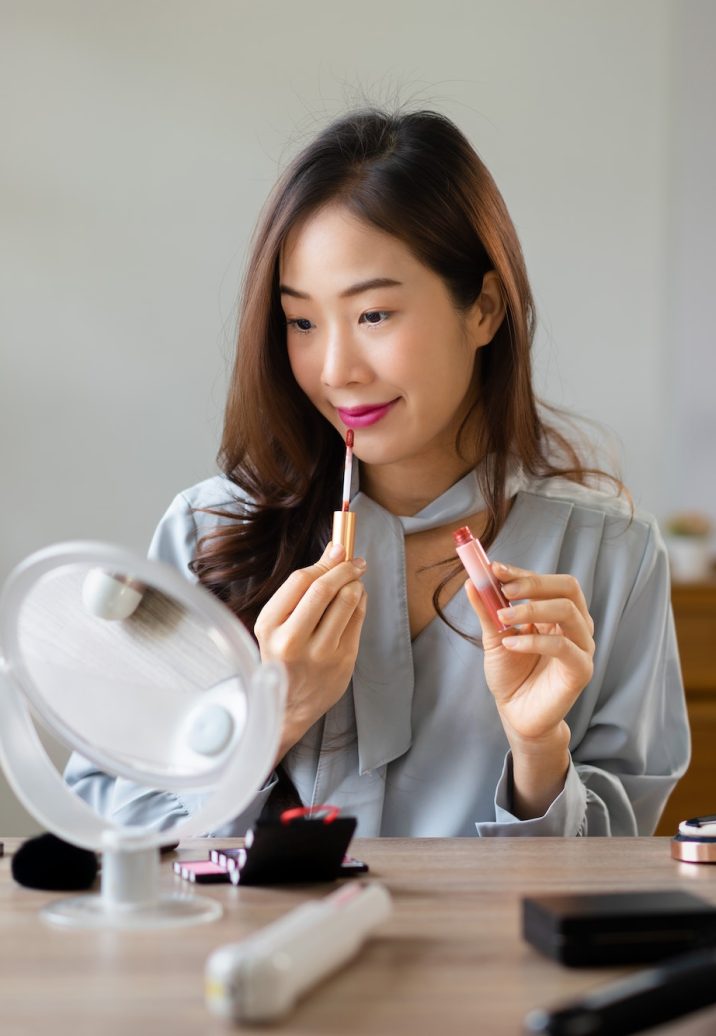 Beauty blogger applying lipstick on her mouth and reviewing cosmetics product in makeup vlogger